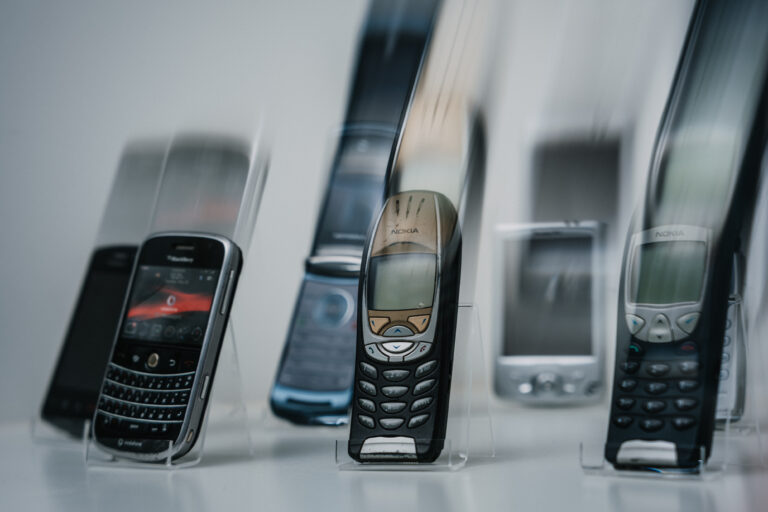 Sammlung &auml;lterer Mobiltelefone, darunter BlackBerry und Nokia, auf transparenten St&auml;ndern