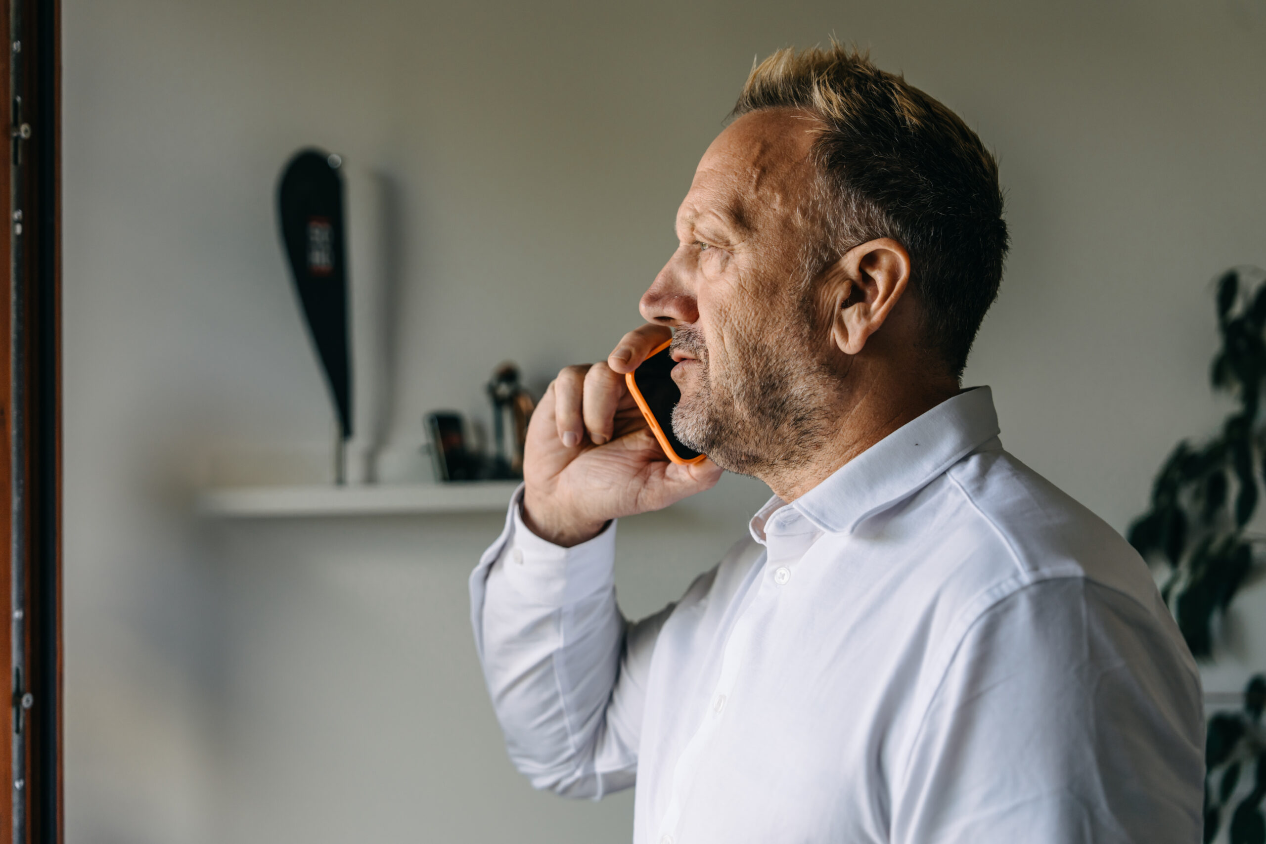 Sven telefoniert mit einem Smartphone am Fenster.